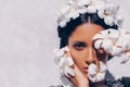 Close up of beautiful young woman wearing wreath and holding frangipani flowers near face at white background