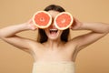 Close up beauty half naked woman 20s with perfect skin nude make up hold grapefruit isolated on beige pastel wall