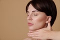 Close-up beauty portrait of a brunette woman with closed eyes doing a lifting rejuvenating massage on her neck, standing three Royalty Free Stock Photo