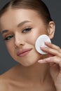 Close up beauty portrait of cute young attractive woman cleaning her face with a cotton pad. Royalty Free Stock Photo
