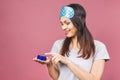 Close up beauty portrait of a laughing beautiful woman in sleeping mask applying face cream and looking away isolated over pink Royalty Free Stock Photo