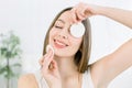 Close up beauty portrait of a smiling attractive woman cleaning her face with a cotton pad isolated over light Royalty Free Stock Photo