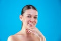 Close up Beauty portrait of young woman brunette smiling and touching her face on blue background. Perfect Fresh Skin Royalty Free Stock Photo