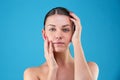 Close up Beauty portrait of young woman brunette smiling and touching her face on blue background. Perfect Fresh Skin Royalty Free Stock Photo