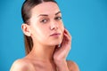 Close up Beauty portrait of young woman brunette smiling and touching her face on blue background. Perfect Fresh Skin Royalty Free Stock Photo