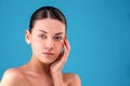 Close up Beauty portrait of young woman brunette smiling and touching her face on blue background. Perfect Fresh Skin Royalty Free Stock Photo