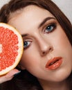 Close-up beauty portrait of young woman with grapefruit with beautiful nude makeup. Modern smokey eyes with colorful eyeshadows Royalty Free Stock Photo