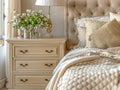 Close up of bedside cabinet near bed with beige bedding. Royalty Free Stock Photo