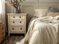 Close up of bedside cabinet near bed with beige bedding. Royalty Free Stock Photo