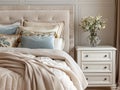 Close up of bedside cabinet near bed with beige bedding. Royalty Free Stock Photo