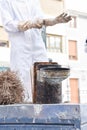 Close-up of a bee smoker over a hive and in the background beekeepers preparing.