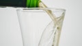 Close-up of beer being poured into clear glass. Action. Beer is poured into transparent glass on white isolated Royalty Free Stock Photo