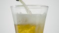 Close-up of beer being poured into clear glass. Action. Beer is poured into transparent glass on white isolated Royalty Free Stock Photo