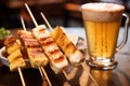 close-up of beer foam with grilled skewers in background