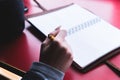 Close-up from behind the back of a young woman in a winter polto is holding a ballpoint pen and is going to write Royalty Free Stock Photo