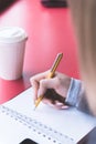 Close-up from behind the back of a young woman in a winter polto is holding a ballpoint pen and is going to write Royalty Free Stock Photo