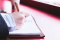 Close-up from behind the back of a young woman in a winter polto is holding a ballpoint pen and is going to write Royalty Free Stock Photo