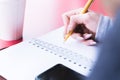 Close-up from behind the back of a young woman in a winter polto is holding a ballpoint pen and is going to write Royalty Free Stock Photo