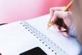 Close-up from behind the back of a young woman in a winter polto is holding a ballpoint pen and is going to write Royalty Free Stock Photo