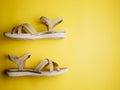 Close up of beige leather summer comfortable women`s sandals on brigth yellow background. Top view, side view, flat lay