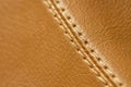 Close-up of beige orange faux leather stitching in the car interior. Background for interior trim comfort