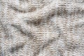 Close up beige sweater knitted made of natural wool texture, wavy folds, selective focus