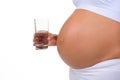 Close-up of belly of a pregnant woman and glass of water Royalty Free Stock Photo