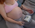 Close-up of the belly of a pregnant woman measuring blood pressure with a tonometer. Hypotension.