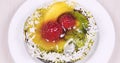 Close up of berry tartlet or cake with fruits and cream jelly on white plate, topview.