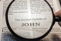 closeup of The second epistle of John from Bible using a magnifying glass to enlarge print.