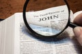 closeup of The third epistle of John from Bible using a magnifying glass to enlarge print.