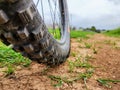 Close up of bicycle tire on dirt road with green grass background. Royalty Free Stock Photo