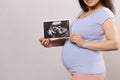 Close-up belly of a smiling pregnant woman holding ultrasound scan image over isolated background. Pregnancy. Childbirth Royalty Free Stock Photo