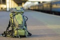 Close-up of big green tourist backpack on railway station platform on blurred background. Traveling, adventure and recreation Royalty Free Stock Photo