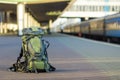 Close-up of big green tourist backpack on railway station platform on blurred background. Traveling, adventure and recreation Royalty Free Stock Photo