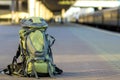 Close-up of big green tourist backpack on railway station platform on blurred background. Traveling, adventure and recreation Royalty Free Stock Photo