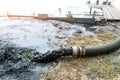 Close-up big pipe of power pump machine pouring mud sludge waste water with sand and silt on ground. Sand-wash and coast