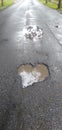 Close up of big pothole with dirty rain water of the road. Royalty Free Stock Photo