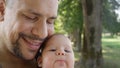 CLOSE UP: Big tattooed father sharing gentle moments with his baby girl in park