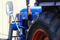 Close up of big tire of blue old ancient  antique tractor with rear view mirror and engine on a farm in Netherlands Royalty Free Stock Photo