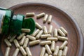 Close up biotin capsules and bottle on clay brown plate on burlap background. Dietary supplements for healthy skin, hair, nail.