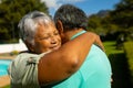 Close-up of biracial senior woman with eyes closed embracing husband in park during sunny day Royalty Free Stock Photo