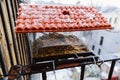 Close up of bird feeder with red tiled roof and plenty seeds inside. Snow during winter season