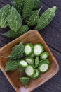 Close up Bitter melon bitter gourd cucumber or Momordica charantia in wooden bowl isolated on old wood table Royalty Free Stock Photo