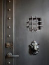 Close up Black ancient cast iron door decorated with metal animal head door knocker, keyhole, handle and small window, Royalty Free Stock Photo