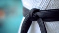 Close-up of a black belt tied on martial arts uniform. Royalty Free Stock Photo