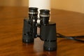 Close up of black binoculars standing up on a wood table Royalty Free Stock Photo