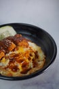 Close Up Of A Black Bowl Food. Rice, Herbs, Vegetables, Cucumber, Chicken Curry, Curry, green peas, celery, green beans on a white