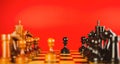 Close up of black chess pieces on board. Two rows of wooden figures on chessboard on red background. Concept of