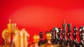 Close up of black chess pieces on board. Two rows of wooden figures on chessboard on red background. Concept of